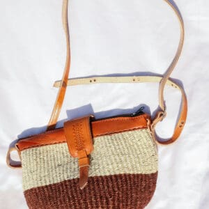 A brown and white purse sitting on top of a bed.