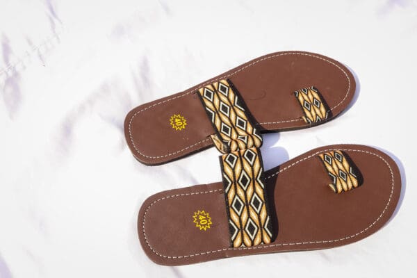 A pair of brown sandals with yellow and black pattern.