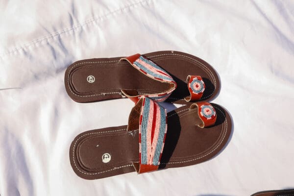 A pair of brown sandals with red, white and blue straps.