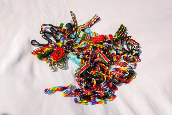 A bunch of colorful bracelets are laying on the bed