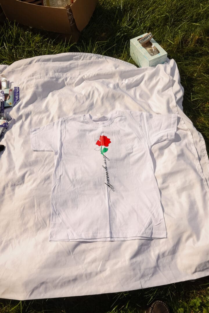 A white t-shirt with a red rose on it.