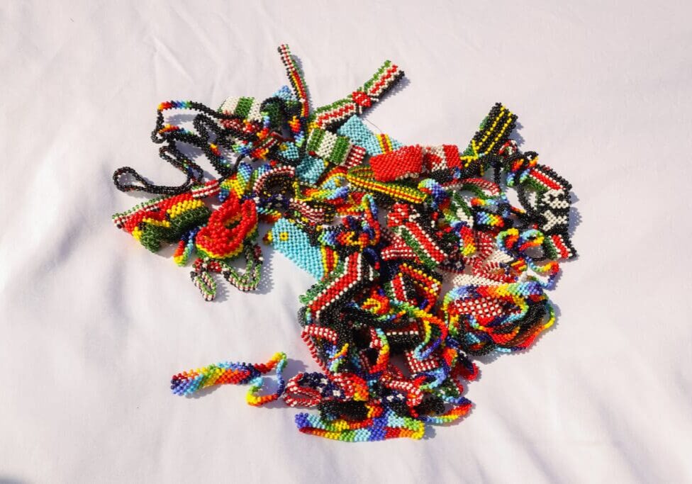 A bunch of colorful bracelets are laying on the bed